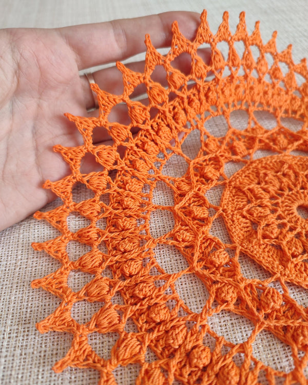 Bright and cheerful round orange crochet doily with a lot of textured 3D elements