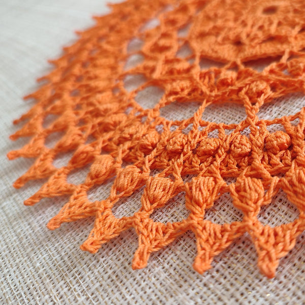 Bright and cheerful round orange crochet doily with a lot of textured 3D elements
