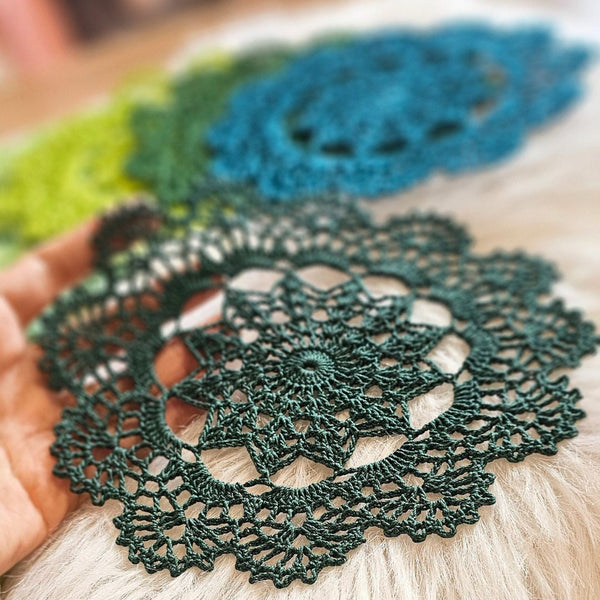 Set of seven round crochet coasters different shade of green each
