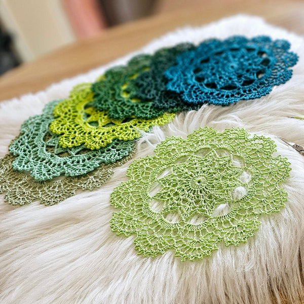 Set of seven round crochet coasters different shade of green each