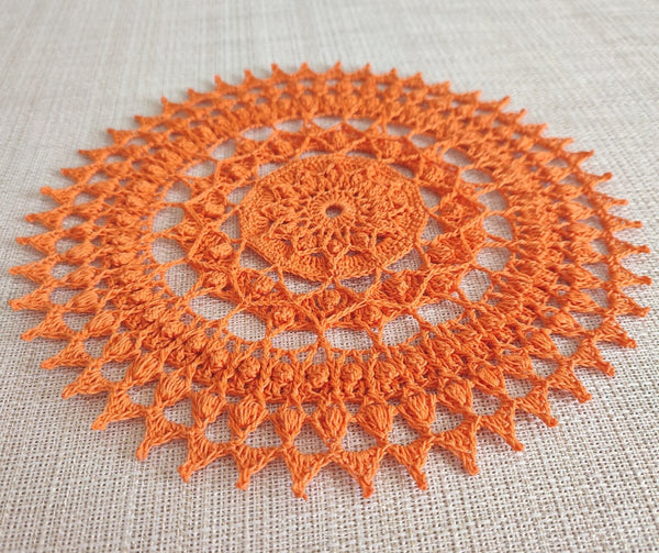 Bright and cheerful round orange crochet doily with a lot of textured 3D elements