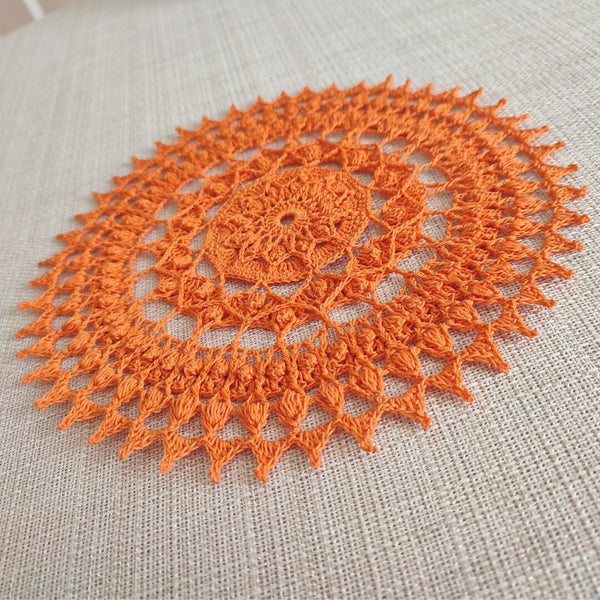 Bright and cheerful round orange crochet doily with a lot of textured 3D elements